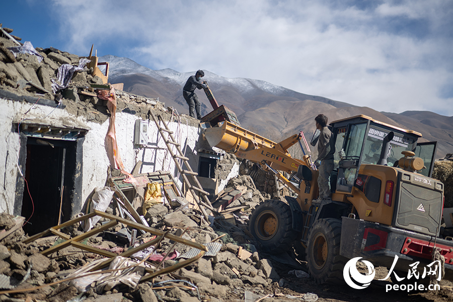 1月13日,长所乡嘎旦村村书记吴坚加布(左)正在村中清理废墟。人民网记者 翁奇羽摄