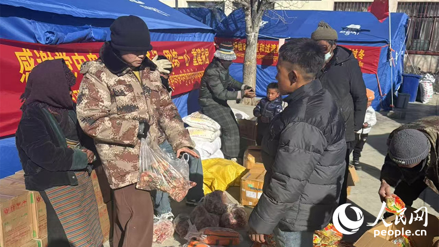 90后乡村振兴专干格桑卓玛(左二)给受灾群众发放物资。人民日报记者 琼达卓嘎摄
